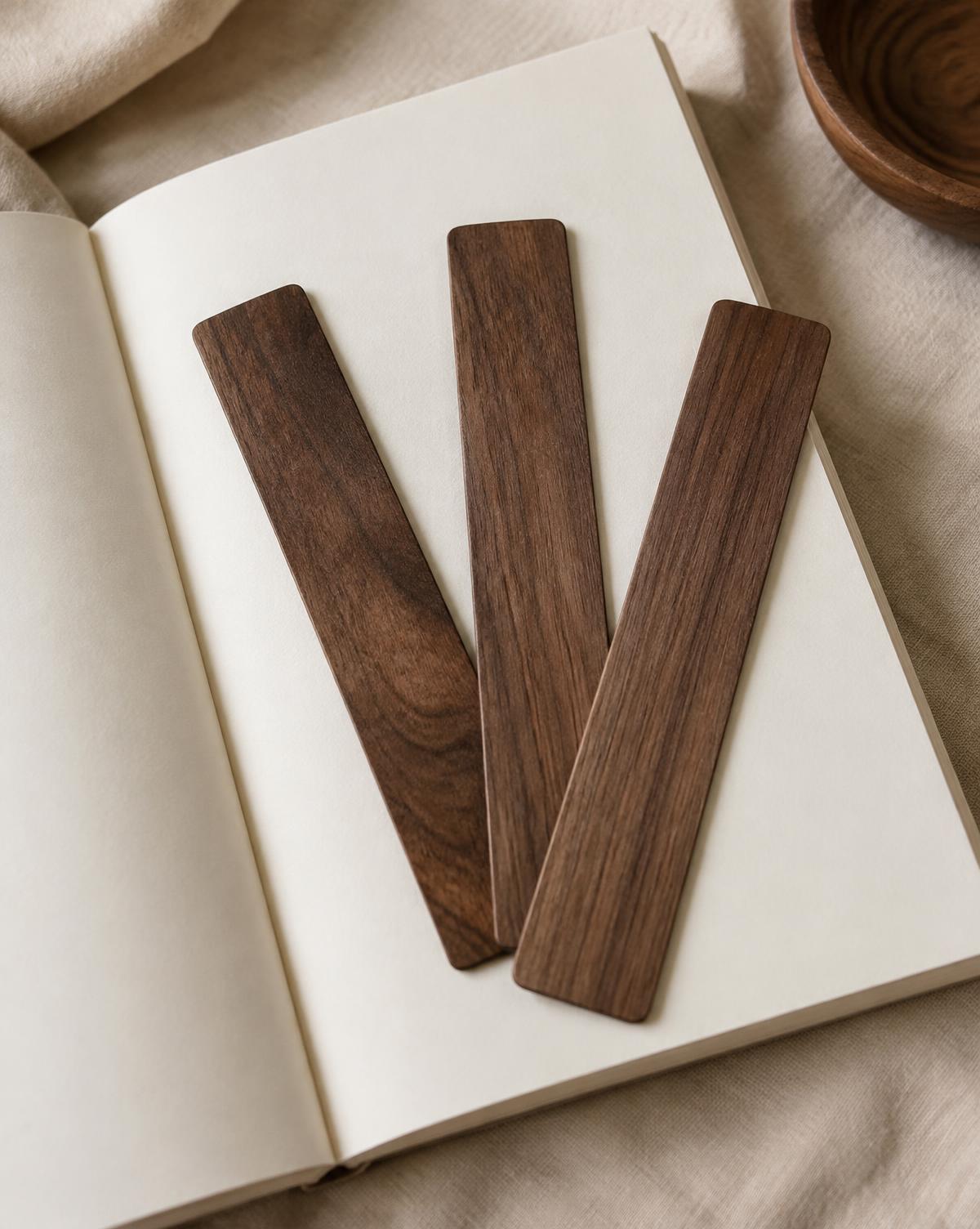 Three thin walnut bookmarks fanned across an open blank book